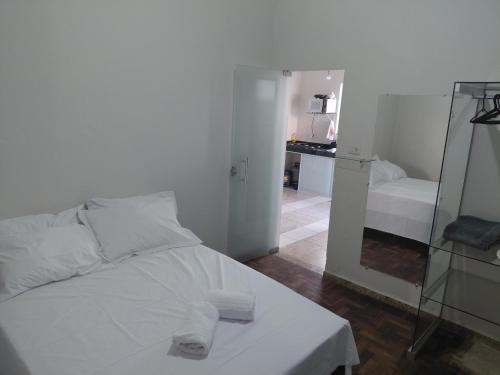 un letto bianco in una stanza con specchio di Kitnet Boa Vista a Sete Lagoas