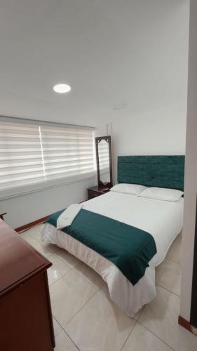 a bedroom with a large bed with a green blanket at Hotel Hierbabuena y Restaurante in Pasto