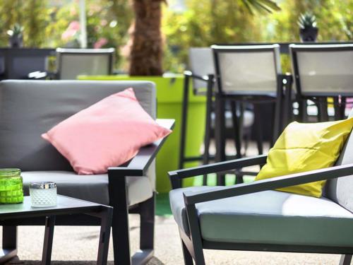 a row of chairs with pink and yellow pillows at ibis Styles Strasbourg Avenue du Rhin in Strasbourg