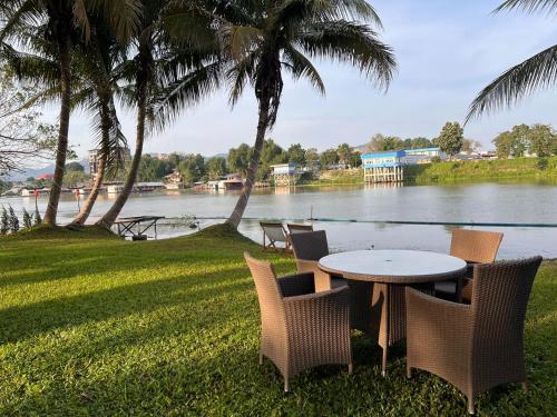 a table and chairs with a view of a river at Merlin Hut & Farm in Kanchanaburi City