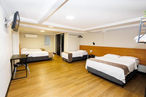 a hotel room with three beds and a desk at Hotel Move BH in Belo Horizonte