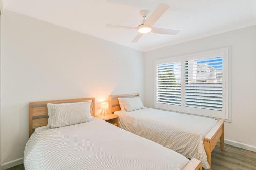 two beds in a room with a window at Endless Horizon in Kingscliff