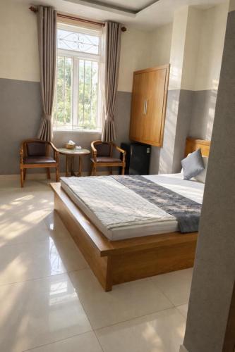 a bedroom with a bed and two chairs and a window at 10h Hotel in Ho Chi Minh City