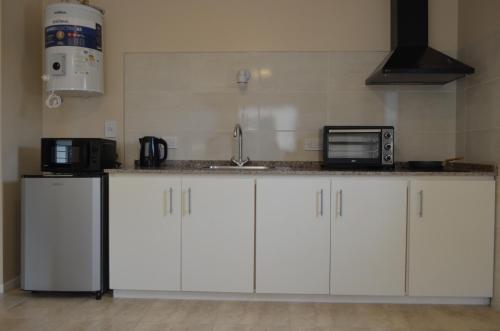 una cucina con armadi bianchi, lavandino e forno a microonde di Happiness suite a San Rafael