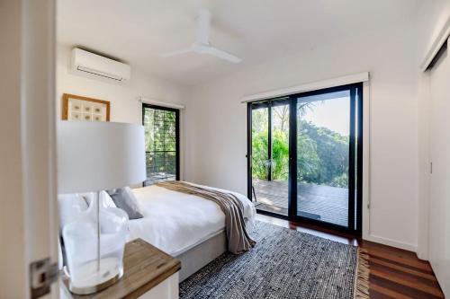 een witte slaapkamer met een bed en een groot raam bij Absolute Beachfront House with Pool & Views in Marcus Beach