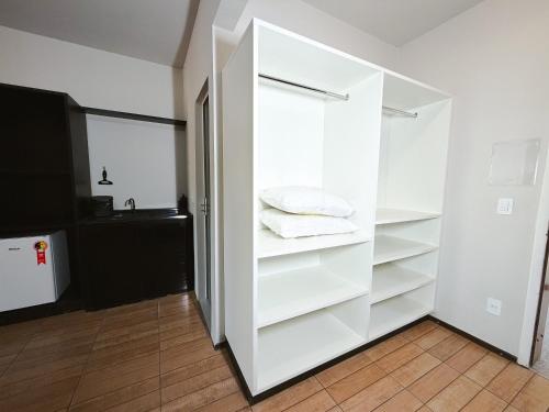 a white closet with white shelves and a sink at Smart Stay Lofts in Joinville