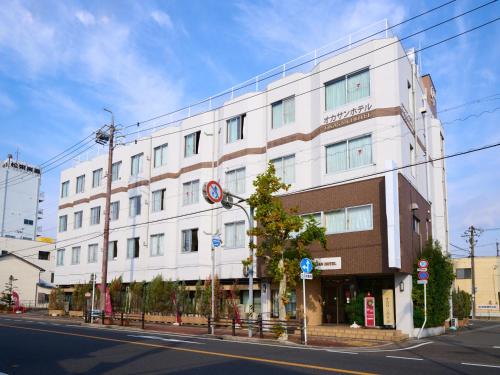 a large white building on the side of a street at Okasan Hotel in Ogaki