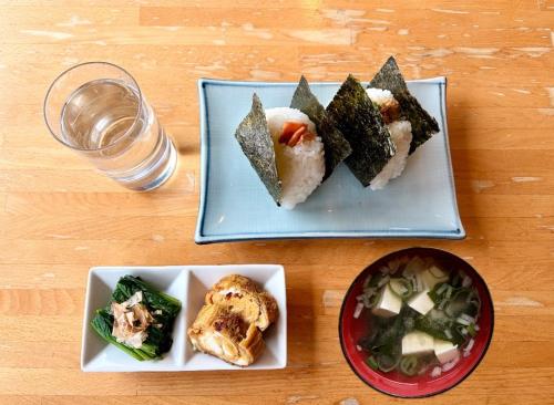 een tafel met drie borden eten en een glas water bij Powder Base Naeba in Yuzawa