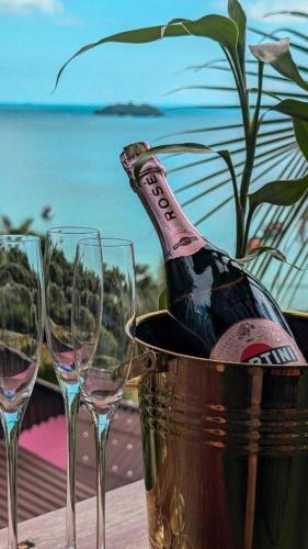 una bottiglia di champagne in un secchiello accanto a tre bicchieri di vino di The Up Koh Rong a Phumĭ Kâoh Rŏng