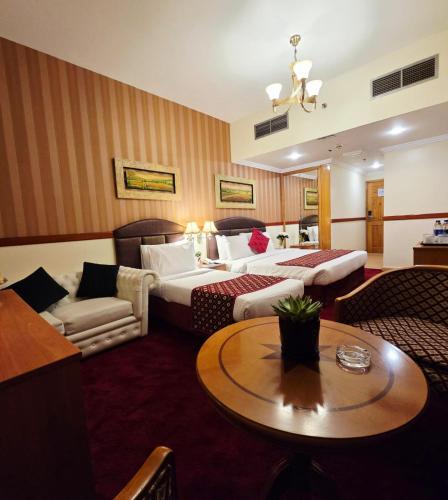 a hotel room with two beds and a table at Golden California Hotel in Dubai
