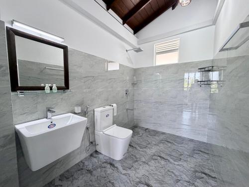 a bathroom with a toilet and a sink and a mirror at Turtle Bay Resort Hikkaduwa in Hikkaduwa