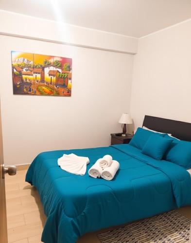 ein Schlafzimmer mit einem blauen Bett mit Handtüchern darauf in der Unterkunft Amplio departamento en Ica in Ica