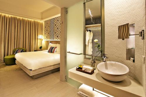 a bathroom with a sink and a bedroom with a bed at Hue Hotels and Resorts Puerto Princesa Managed by HII in Puerto Princesa City