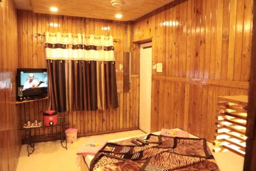 ein Schlafzimmer mit holzgetäfelten Wänden und einem Fernseher in der Unterkunft ALTAF's MOTEL in Matheran