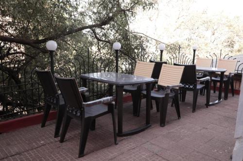 eine Reihe von Tischen und Stühlen auf einer Terrasse in der Unterkunft ALTAF's MOTEL in Matheran