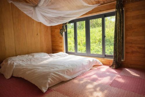 a bed in a room with a large window at Tả Mẩy Homestay in Lao Cai