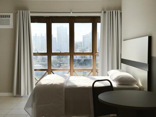 a bedroom with a bed and a large window at Smart Stay Lofts in Joinville