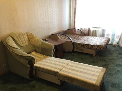 ウフタにあるApartment On Oktyabrskaya 34の椅子とベッド、窓が備わる客室です。