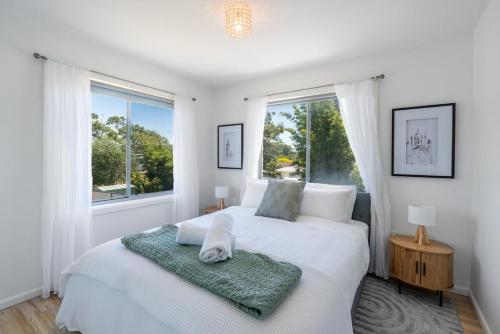 een witte slaapkamer met een bed en een raam bij Seven Miles Beach Escape in Shoalhaven Heads