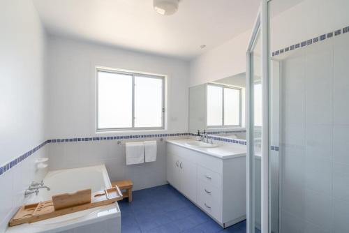 een witte badkamer met een wastafel en een douche bij Seven Miles Beach Escape in Shoalhaven Heads