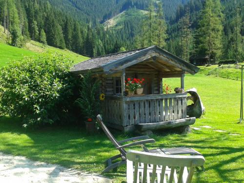 a small cabin in the middle of a field with two chairs at Biobauernhof Windbachgut in Eben im Pongau