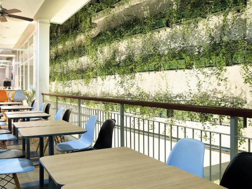 un restaurant avec des tables et des chaises et un mur végétal dans l'établissement Ibis Bandung Pasteur, à Bandung