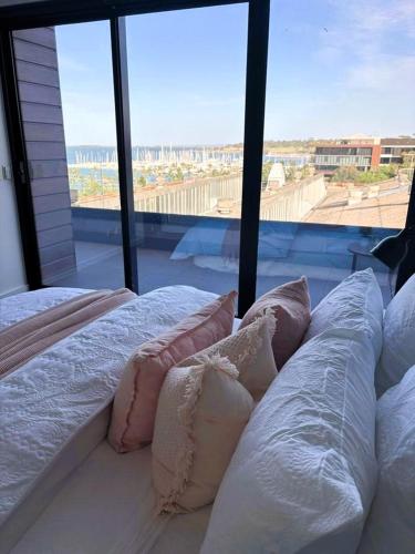 a bedroom with two beds with pillows and a large window at PIER POINT 3 Bedroom Deluxe Apartment located on The Geelong Waterfront - 106 in Geelong
