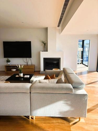 a living room with a couch and a flat screen tv at PIER POINT 3 Bedroom Deluxe Apartment located on The Geelong Waterfront - 106 in Geelong