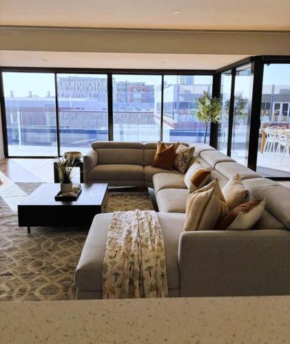 a living room with a couch and a table at PIER POINT 3 Bedroom Deluxe Apartment located on The Geelong Waterfront - 106 in Geelong
