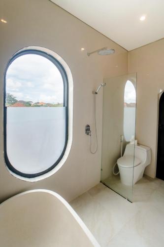 a bathroom with a toilet and a window at Modern 1BR Loft style with pool in Pegending in Dalung