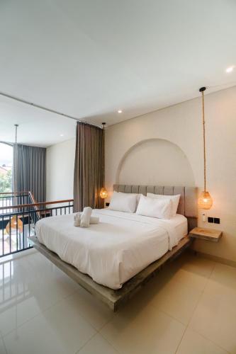 a bedroom with a large white bed with a balcony at Modern 1BR Loft style with pool in Pegending in Dalung