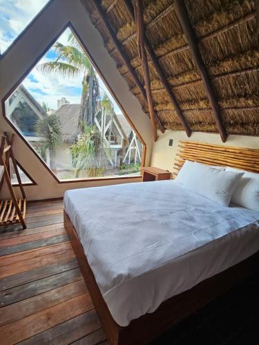 ein Schlafzimmer mit einem großen Bett und einem großen Fenster in der Unterkunft Kaaj Ndomi in Bacalar