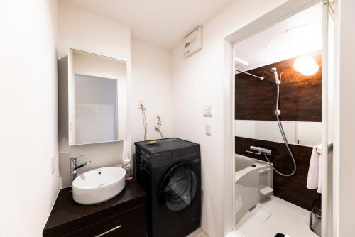 ein Badezimmer mit Waschmaschine und Waschbecken in der Unterkunft AYA HOTELS 博多 1st in Fukuoka