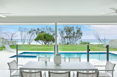 a dining room with a table and a swimming pool at Sentosa on Tugun in Gold Coast
