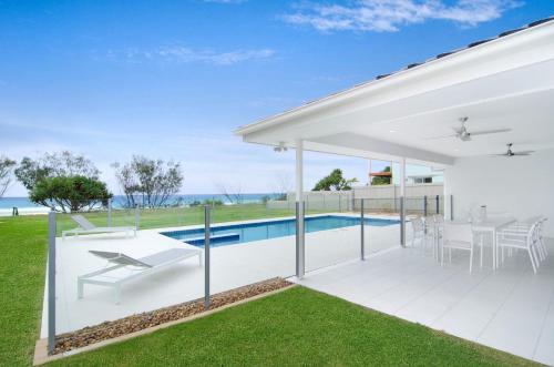 a white house with a swimming pool and a patio at Sentosa on Tugun in Gold Coast