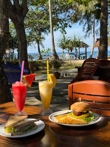 una mesa con un sándwich y dos vasos de zumo en Season Bungalow, en Ko Jum