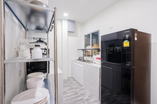 a kitchen with white cabinets and a black refrigerator at Sea Fan Cha-am Pool Villa in Ban Bo Prakhon