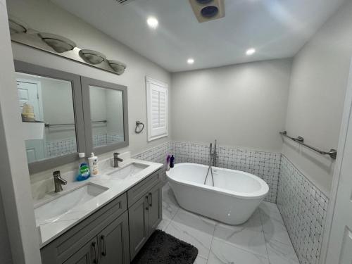 a white bathroom with a tub and a sink and a bath tub at Pearson Gateway Comfort Home in Mississauga