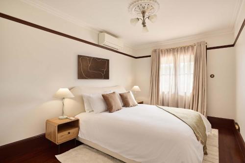a bedroom with a white bed and a window at Grand 4BR Paddington Terrace - Free parking in Sydney