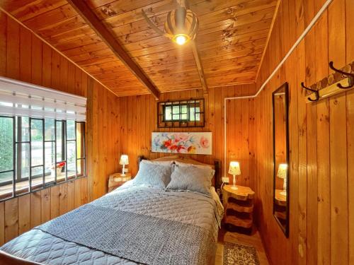 a bedroom with a bed in a wooden wall at Refugio araucano - Lican Ray in Licán Ray