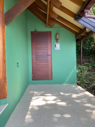 Ladylagoon Villas في كوه ساموي: جدار أخضر مع باب خشبي على منزل
