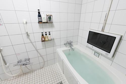 baño con bañera y TV en la pared en HOTEL555 錦糸町, en Tokio