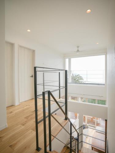 a spiral staircase in a white room with a window at 新築サーファーズハウス棟貸しFLAG Awaji in Awaji