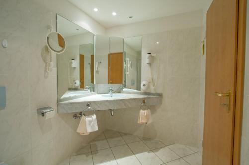 ein Bad mit einem Waschbecken und einem Spiegel in der Unterkunft Hotel Hahnenkleer Hof in Hahnenklee-Bockswiese