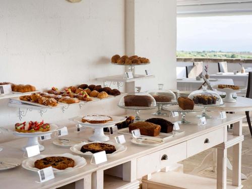 a buffet filled with different types of pastries and pies at Borgobianco Resort & Spa Polignano - MGallery Collection in Polignano a Mare