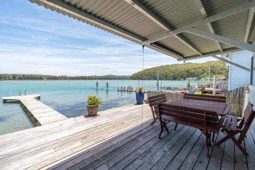 a wooden dock with a bench and the water at The Fishin' Shack in Burrill Lake