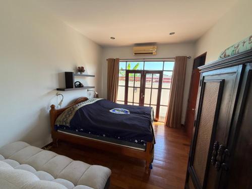 a bedroom with a bed and a couch and a window at Private Pool-Villa Baan Roth, Gated community 24/7 in Hua Hin