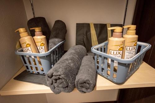 two baskets on a shelf with cleaning products and towels at Pine21 TOHOKU 