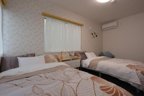 a bedroom with two beds and a window at Pine21 TOHOKU 
