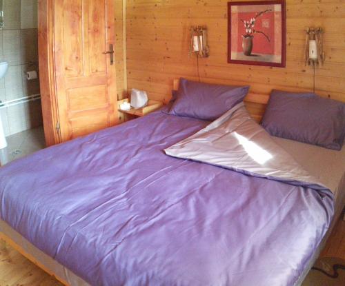 a large bed with purple sheets in a bedroom at Pensiunea Moldovan in Praid